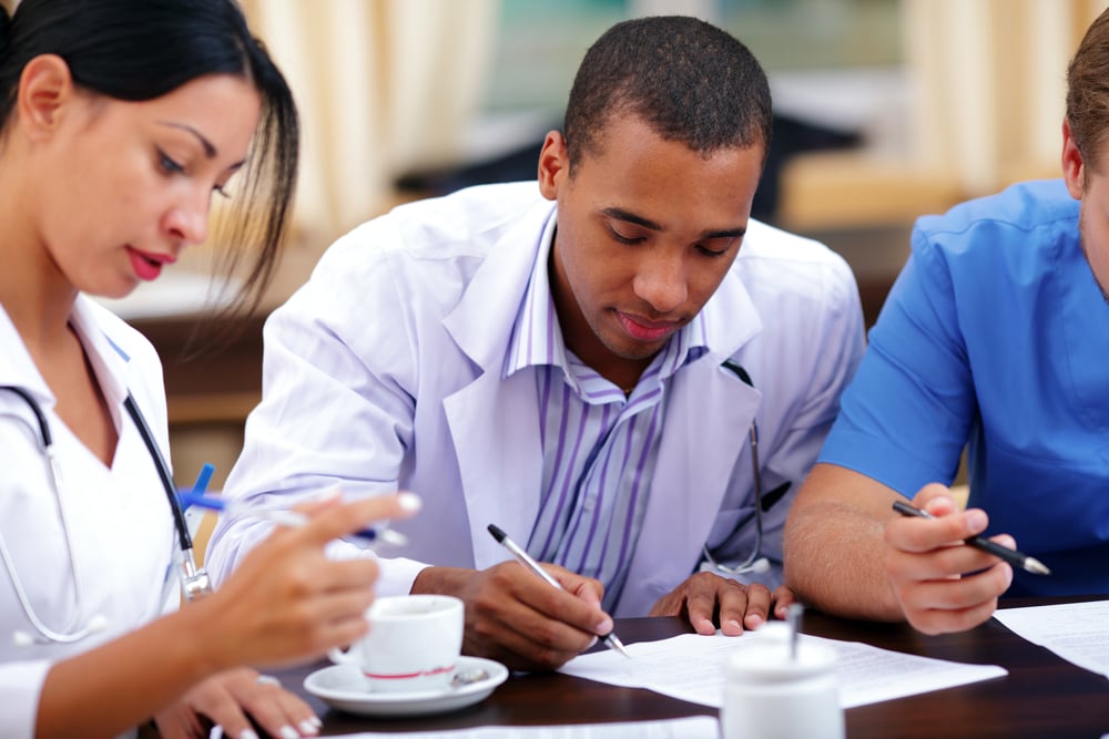 Young african-american doctor making notes at the medical meeting